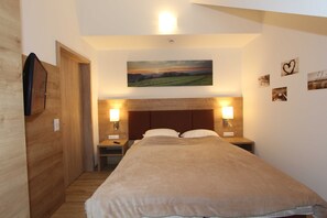 A bedroom with a bed, two bedside lamps, a painting on the wall, and a wooden door. - GRA-312 - Modern vacation apartment with a hot tub (excl. tax) - Grafenmatt 3.2 Residence (Feldberg (Schwarzwald))
