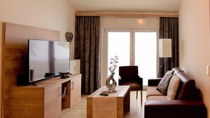 A modern living room with a flat-screen TV, a sofa, a coffee table, and a chair. - GRA-312 - Modern vacation apartment with whirlpool (HT) - Residence Grafenmatt 3.2 (Feldberg (Schwarzwald))