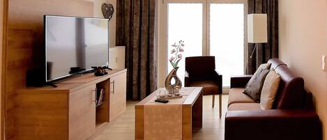 Una sala de estar moderna con un televisor de pantalla plana, un sofá, una mesa de centro y una silla.