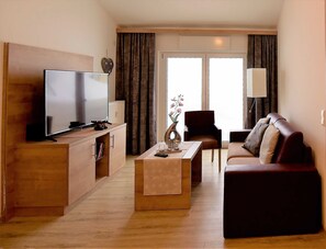 A modern living room with a flat-screen TV, a sofa, a coffee table, and a chair. - GRA-312 - Modern vacation apartment with whirlpool (HT) - Residence Grafenmatt 3.2 (Feldberg (Schwarzwald))