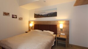 A bedroom with a bed, two bedside tables, a nightstand, a wall-mounted painting, and a ceiling light fixture. - GRA-312 - Modern vacation apartment with whirlpool (HT) - Residence Grafenmatt 3.2 (Feldberg (Schwarzwald))