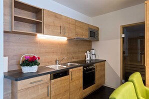 A modern kitchen with wooden cabinets, a built-in microwave, a dishwasher, and a coffee maker.