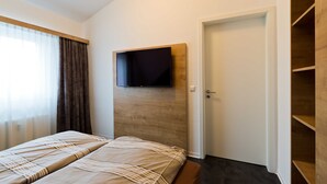 Et hotelværelse med en seng, et ophængt fjernsyn, en dør og et træskab.