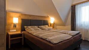 Une chambre à coucher avec un lit, des lampes de chevet, une table de nuit et une fenêtre avec des rideaux.