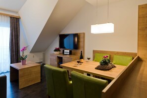 Una habitación moderna con una mesa de comedor, sillas verdes, un televisor y un mueble de madera.