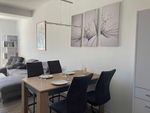 Un comedor con una mesa de madera, cuatro sillas y tres cuadros en la pared.