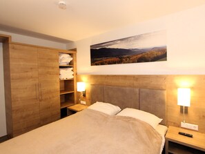 A hotel room with a bed, wooden wardrobe, and a painting of a landscape. - GRA-210 - Vacation apartment with south-east-facing balcony and whirlpool - Grafenmatt Residence (Feldberg (Schwarzwald))