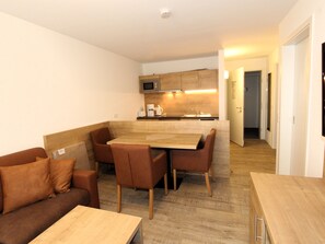 A compact living space with a kitchenette, a dining area, and a sofa.