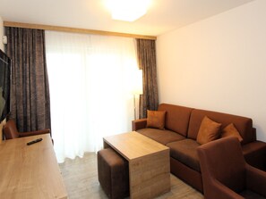 A modern living room with a wooden coffee table, brown sofa, and a TV on a stand. - GRA-210 - Vacation apartment with south-east-facing balcony and whirlpool - Grafenmatt Residence (Feldberg (Schwarzwald))