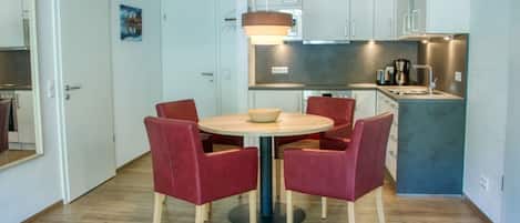 A compact kitchen with white cabinets, a round table with four chairs, and a small island with a sink.
