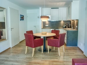 Una cocina compacta con armarios blancos, una mesa redonda con cuatro sillas y una pequeña isla con fregadero.