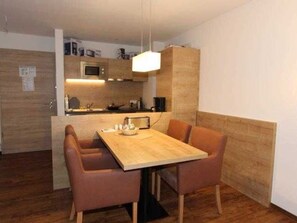 A compact kitchen with a microwave, stove, and wooden cabinets. There is a dining area with a table and four chairs.