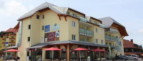 A multi-story hotel with outdoor seating and a sign for a restaurant.