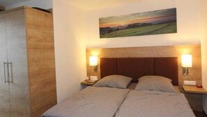 A bedroom with a bed, two bedside tables, a nightstand, a wardrobe, and a painting on the wall. - GRA-217 - Comfortable apartment with whirlpool - Residence Grafenmatt 2.2 (Feldberg (Schwarzwald))