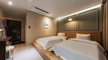 A hotel room with two beds, a desk, and a wardrobe.