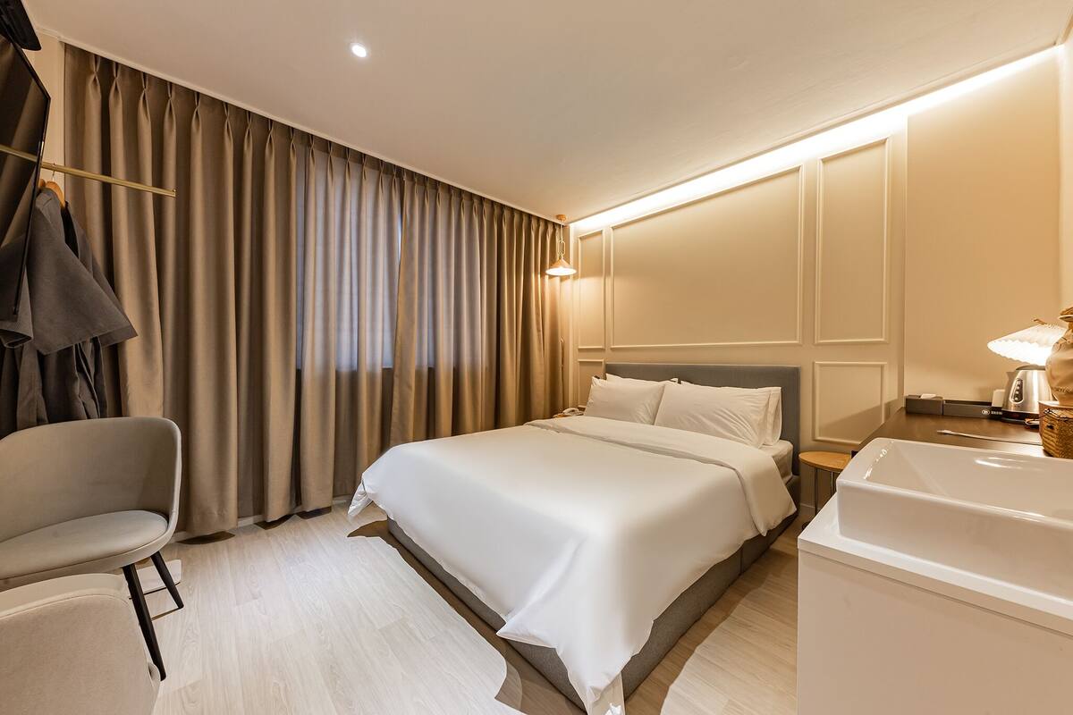 A hotel room with a bed, a chair, a desk, and a bathtub.