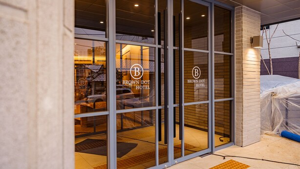 The exterior of the Brown Dot Hotel with large glass doors and a brick facade. - Brown Dot Hotel (Jecheon)