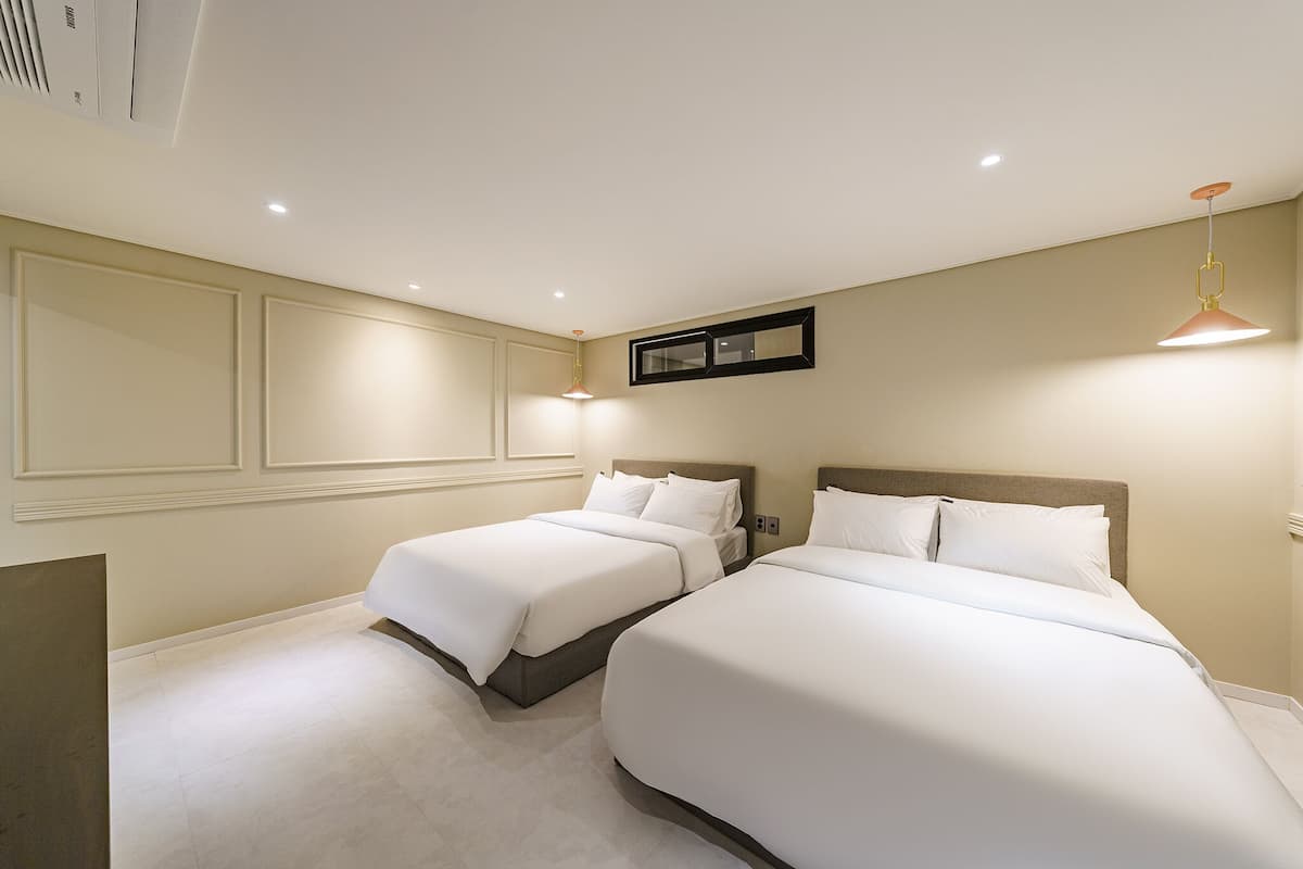 A hotel room with two beds, a large mirror, and recessed ceiling lighting.