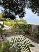 Un jardín con muro de piedra, terraza de madera y piscina.