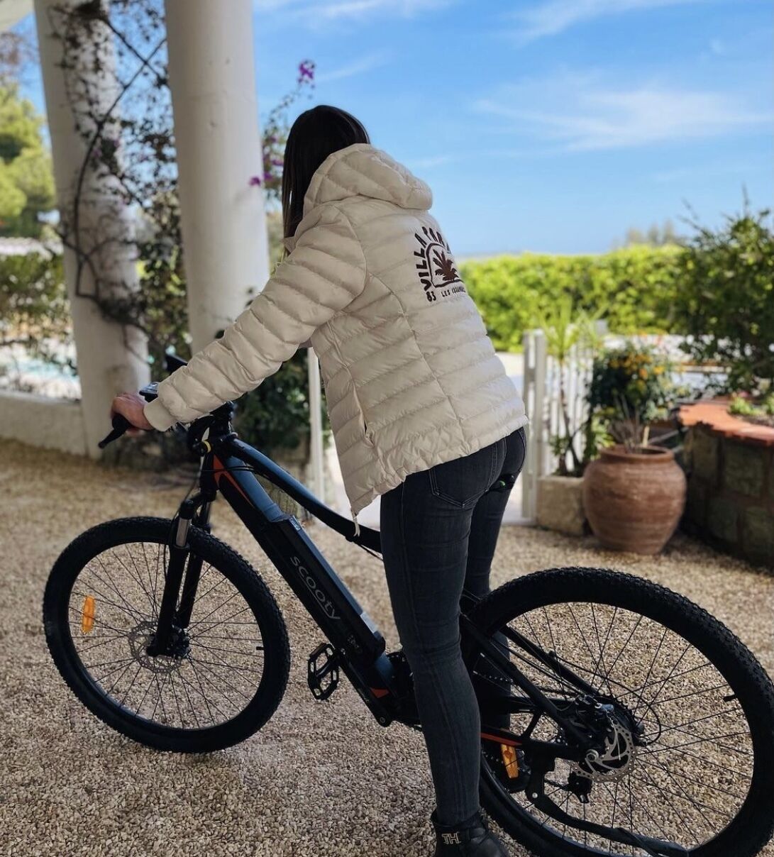 Una persona está de pie junto a una bicicleta eléctrica estacionada al aire libre.