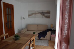 Un soggiorno con un divano, un tavolo da pranzo con sedie, una lampada e un quadro appeso al muro.
