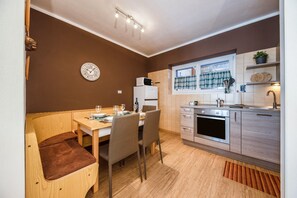 A compact kitchen with a dining area, a microwave, and a clock on the wall.