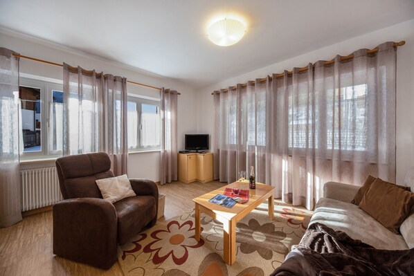 A living room with a sofa, armchair, coffee table, and curtains.