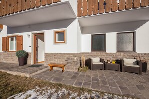 A building with a porch, a door, a window, and outdoor furniture.