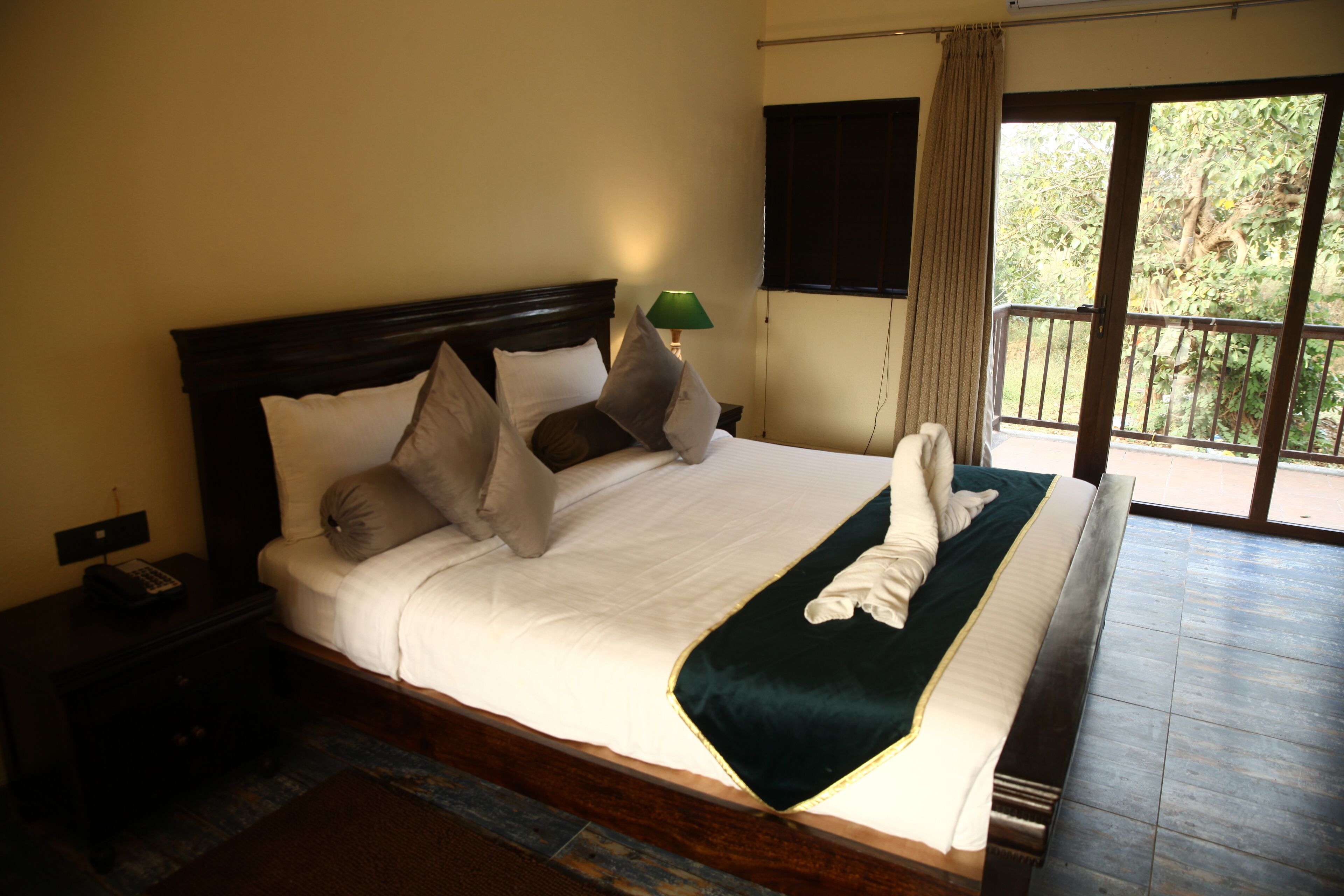 A large bed with a green throw blanket, multiple pillows, and a bedside lamp.
