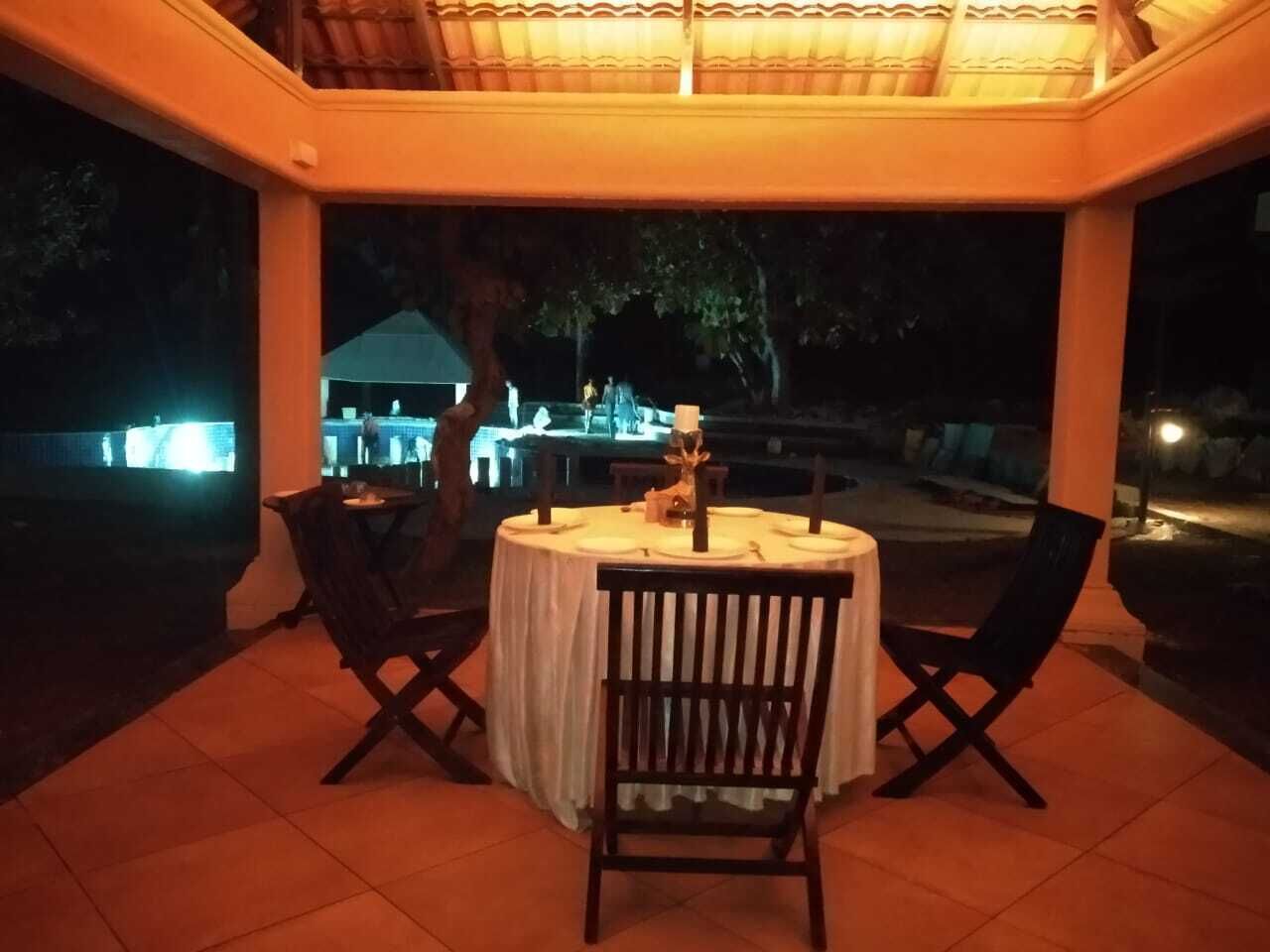 Een terras met een ronde tafel en twee stoelen, overdekt met een betegelde vloer.
