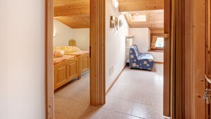 A wooden interior with a bed, a small table, and a chair.