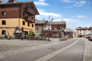 Une rue bordée d’immeubles, dont un bâtiment jaune portant une enseigne indiquant « Banca Popolare di Sondrio ».