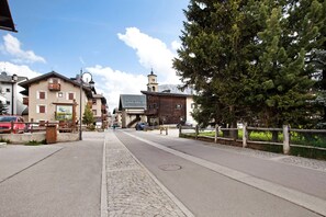 A street with buildings, a clock tower, and a paved sidewalk.