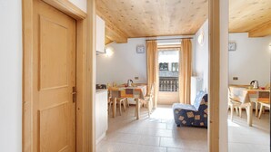 A wooden interior with a dining area, a sofa, and a view through a window.
