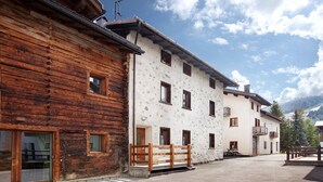 A wooden building with a stone facade, a wooden bench, and a clear sky.