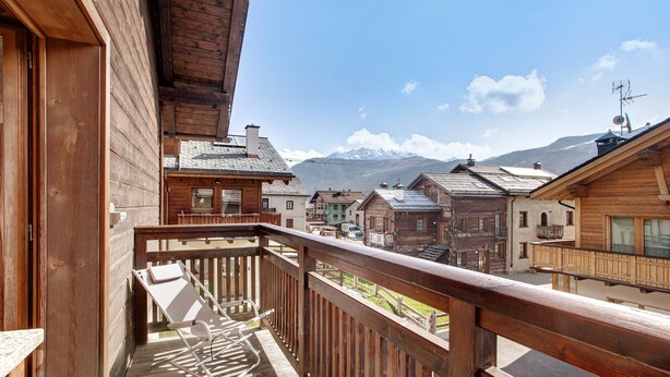 Ein Holzbalkon mit Blick auf traditionelle Gebäude und Berge.