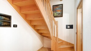 Eine Holztreppe mit Handlauf, einem Wandbild und einer Tür.