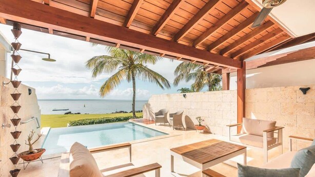 Un espace piscine extérieur avec vue sur l’océan, une pergola en bois et des coins salon.