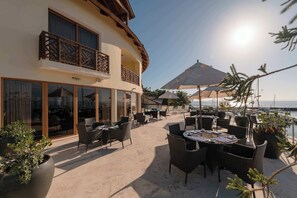 Un patio de hotel con mobiliario exterior, ventanas amplias y vista al mar.
