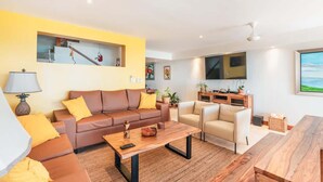 Un salon moderne avec un canapé, un fauteuil, une table basse et un téléviseur.