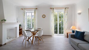 A dining area with a round table and chairs, a fireplace, and a sofa with a lamp. - Apartment 'Old Village T2 Duplex' with Shared Pool, Wi-Fi and Air Conditioning (Quarteira)