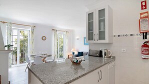 A kitchen with a granite countertop, white cabinets, a coffee maker, and a fire extinguisher. - Apartment 'Old Village T2 Duplex' with Shared Pool, Wi-Fi and Air Conditioning (Quarteira)