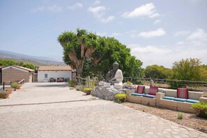 Un cortile con una statua, una zona relax e un edificio con tetto in tegole.