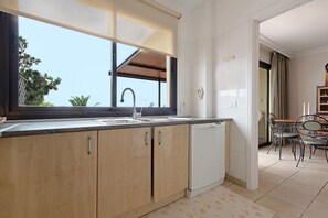 A modern kitchen with wooden cabinets, a built-in dishwasher, and a large window.