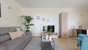 Un salon moderne avec un canapé, une table basse, un téléviseur et une plante en pot.