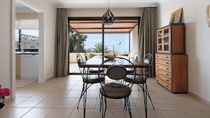Un coin repas comprenant une table et des chaises, un buffet en bois et une vue à travers une porte vitrée.