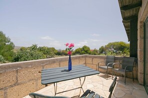 Une terrasse avec une table, des chaises et un vase rempli de fleurs.