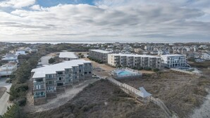 A coastal residential area with modern multi-story buildings, a swimming pool, and a beach access walkway. - 2952 - Davis - Coastal Condo in Duck Steps from the Beach (Duck)