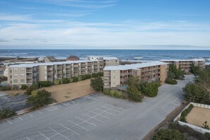Un ensemble d’appartements situé sur la côte, composé de plusieurs bâtiments, avec un parking et une vue sur l’océan.
