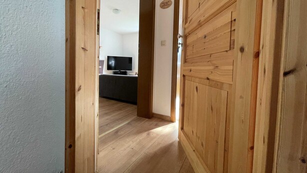 Eine Holztür, die zu einem Raum mit einem Fernseher und einem kleinen Tisch führt.